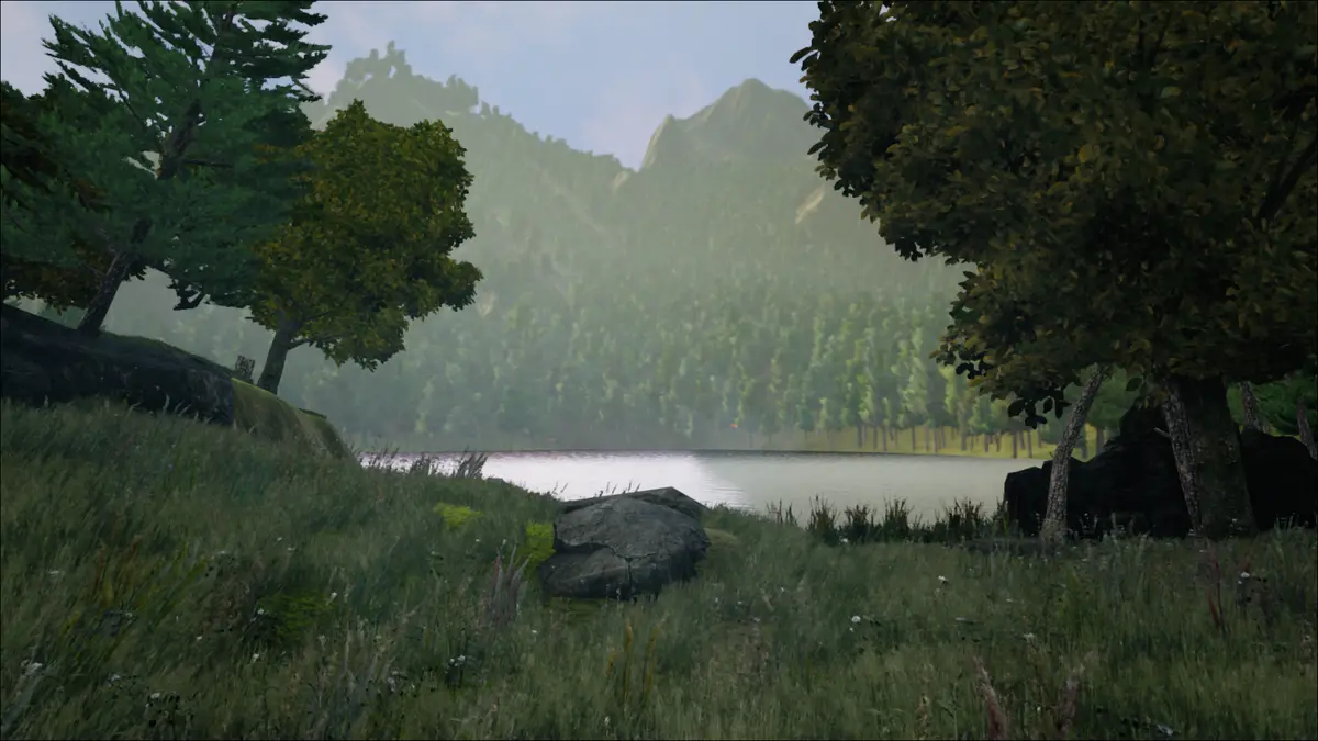 A still lake ringed by forested hills and misty mountains