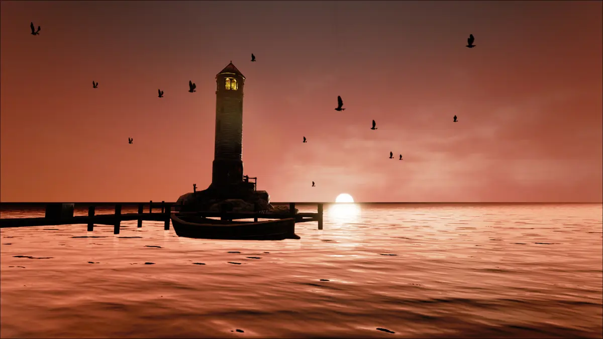 A lighthouse on a jetty silhouetted against a sunset over water