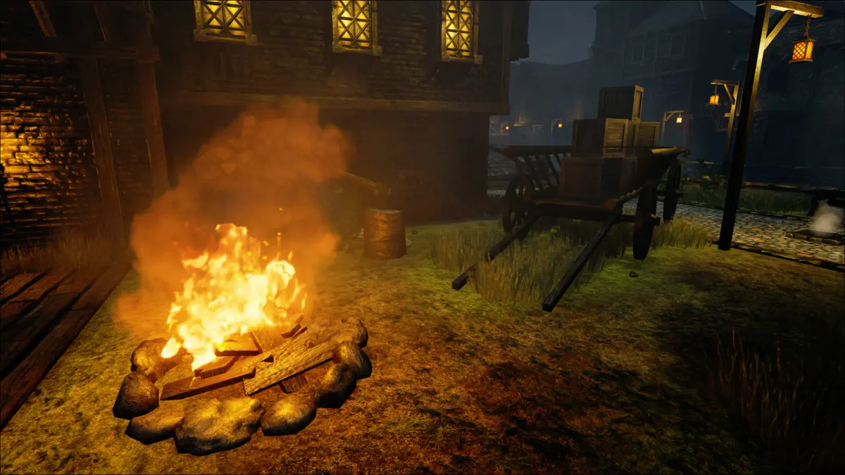 A campfire burns beside a wooden cart in a village at night